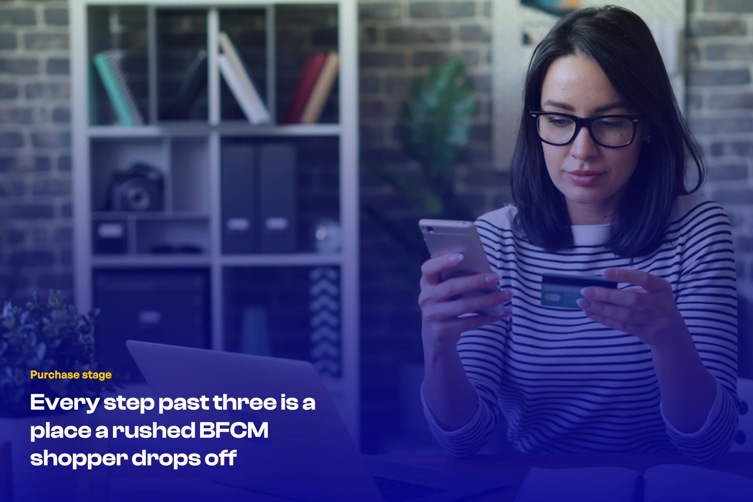 A shopper checking out on a mobile phone, holding a credit card, testing the purchase stage on their own store before BFCM