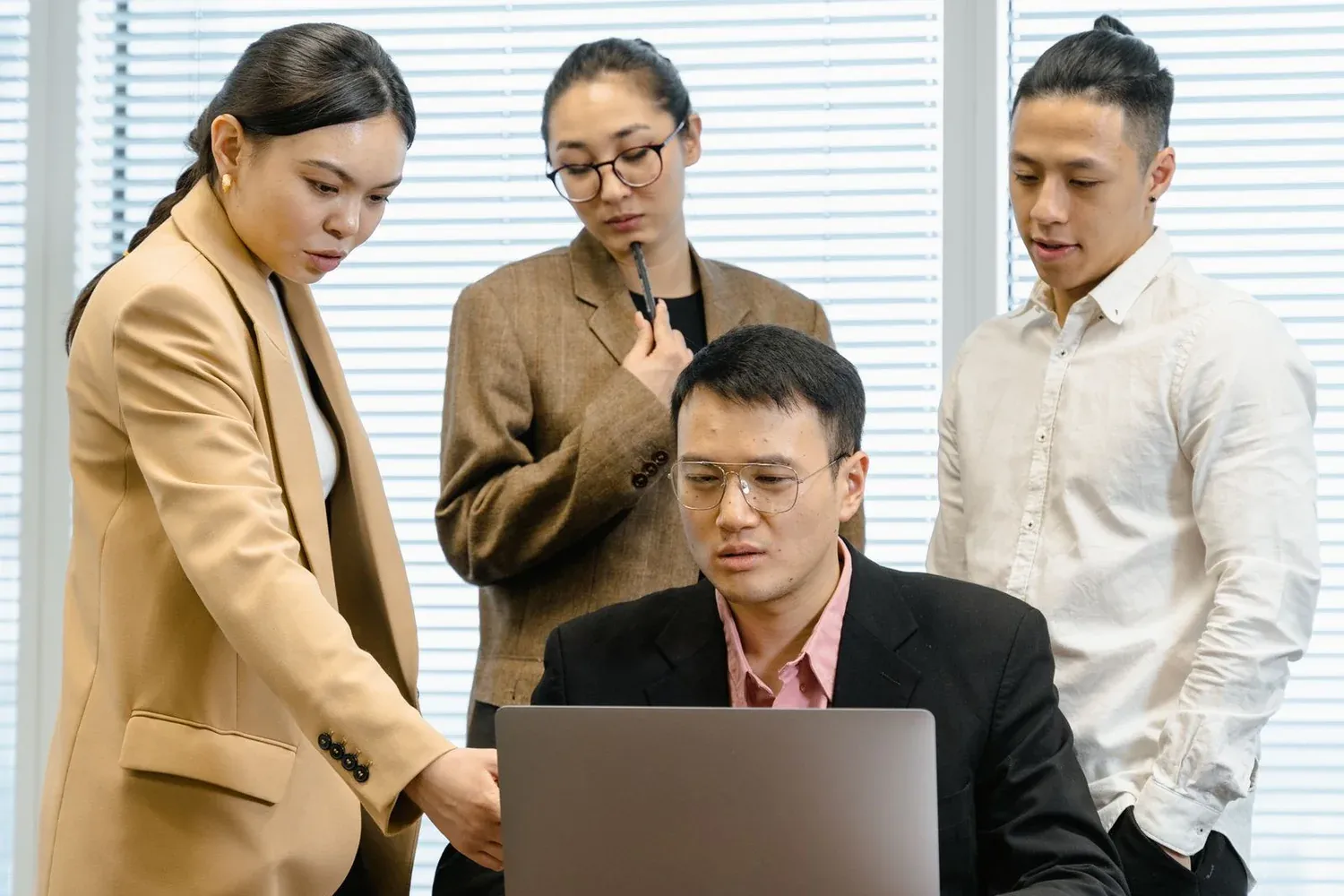 A team gathered around a laptop during a dress rehearsal, focused and discussing what they're seeing on screen together